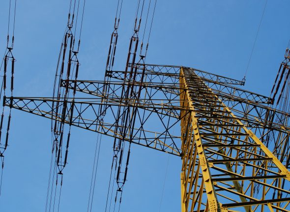 Silhouette of a high-voltage pylon in the blue evening sky.